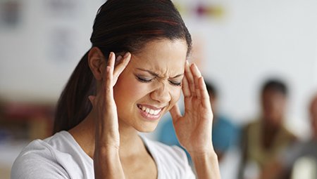 Woman grimacing and holding head in pain