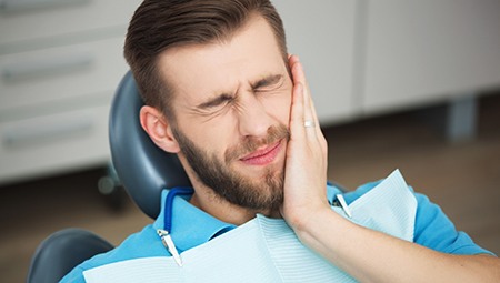 Grimacing man holding his face