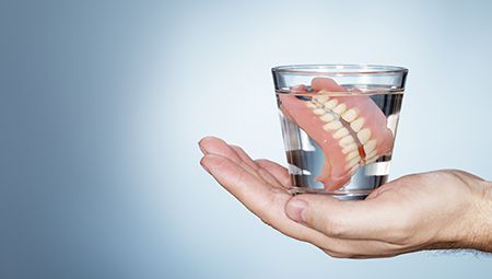 Full set of dentures in glass of water