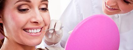 Woman and dentist looking at her teeth in mirror
